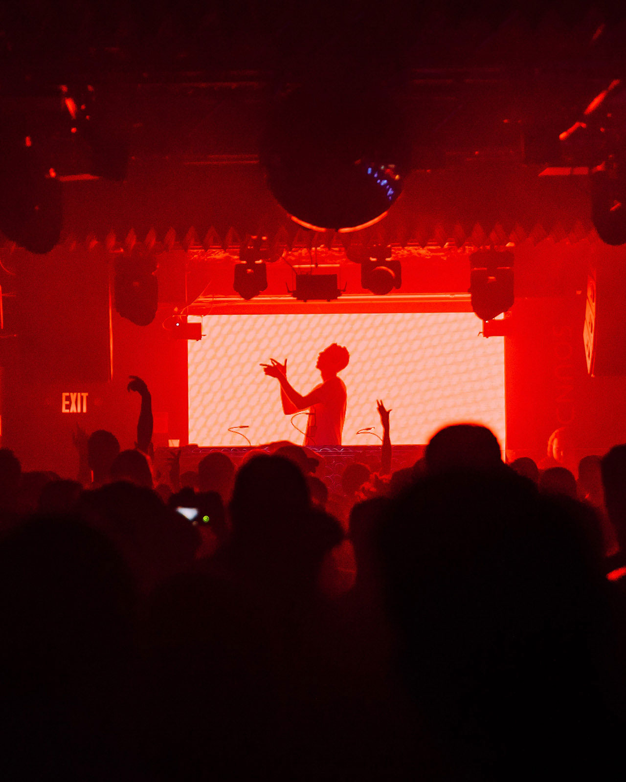 A shot of a DJ spinning with a red glow over he and the crowd.